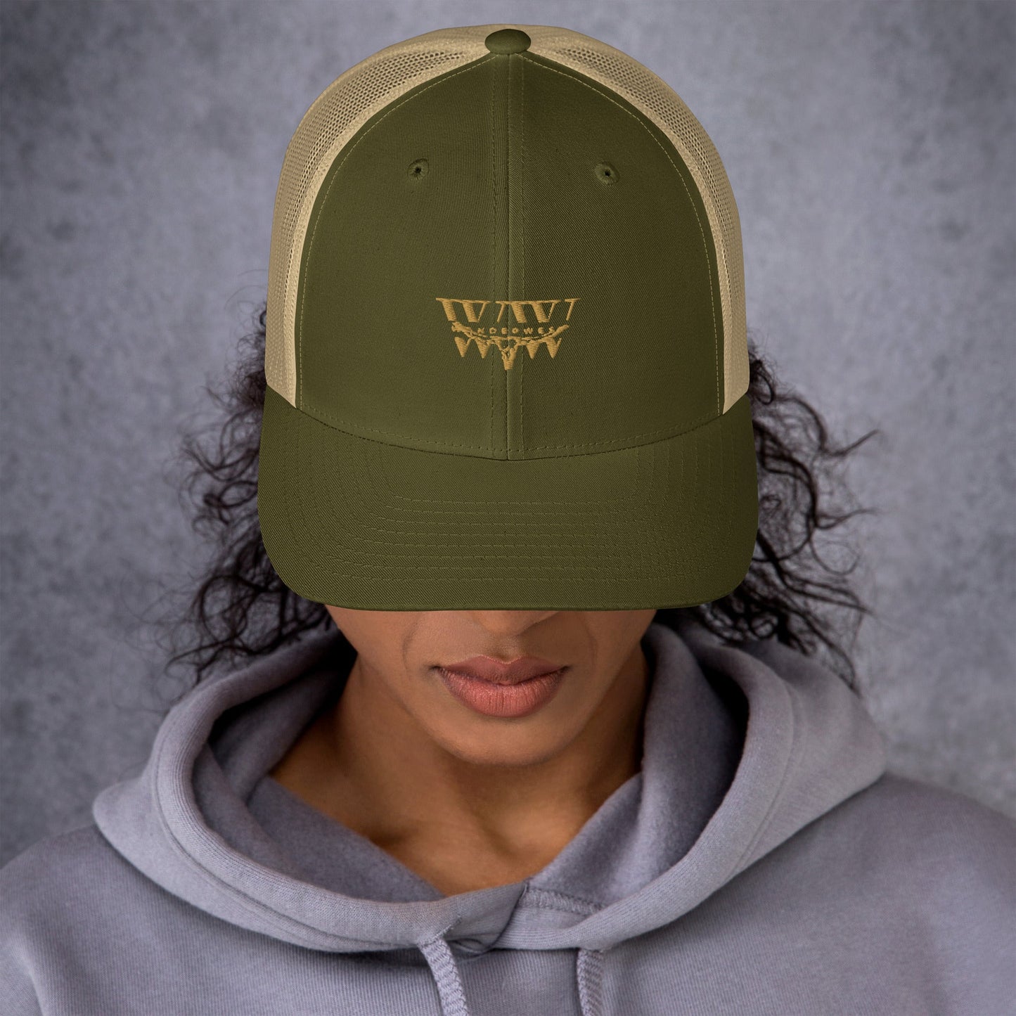 WanderWest Logo Trucker Cap with mesh back and olive color, worn by a person in a hoodie.