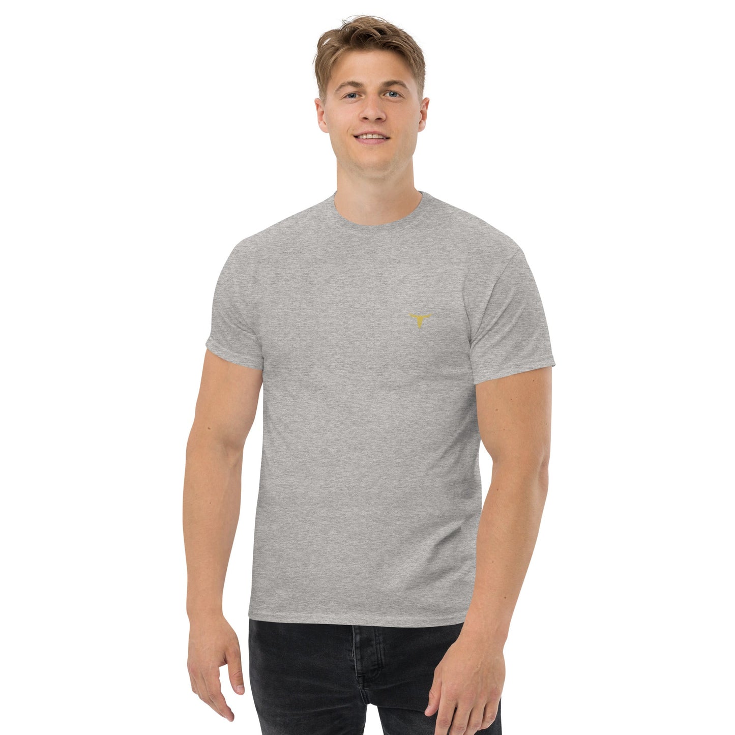 Man wearing a grey Bull Horn Unisex classic tee with a small yellow bull horn logo on the chest and black jeans